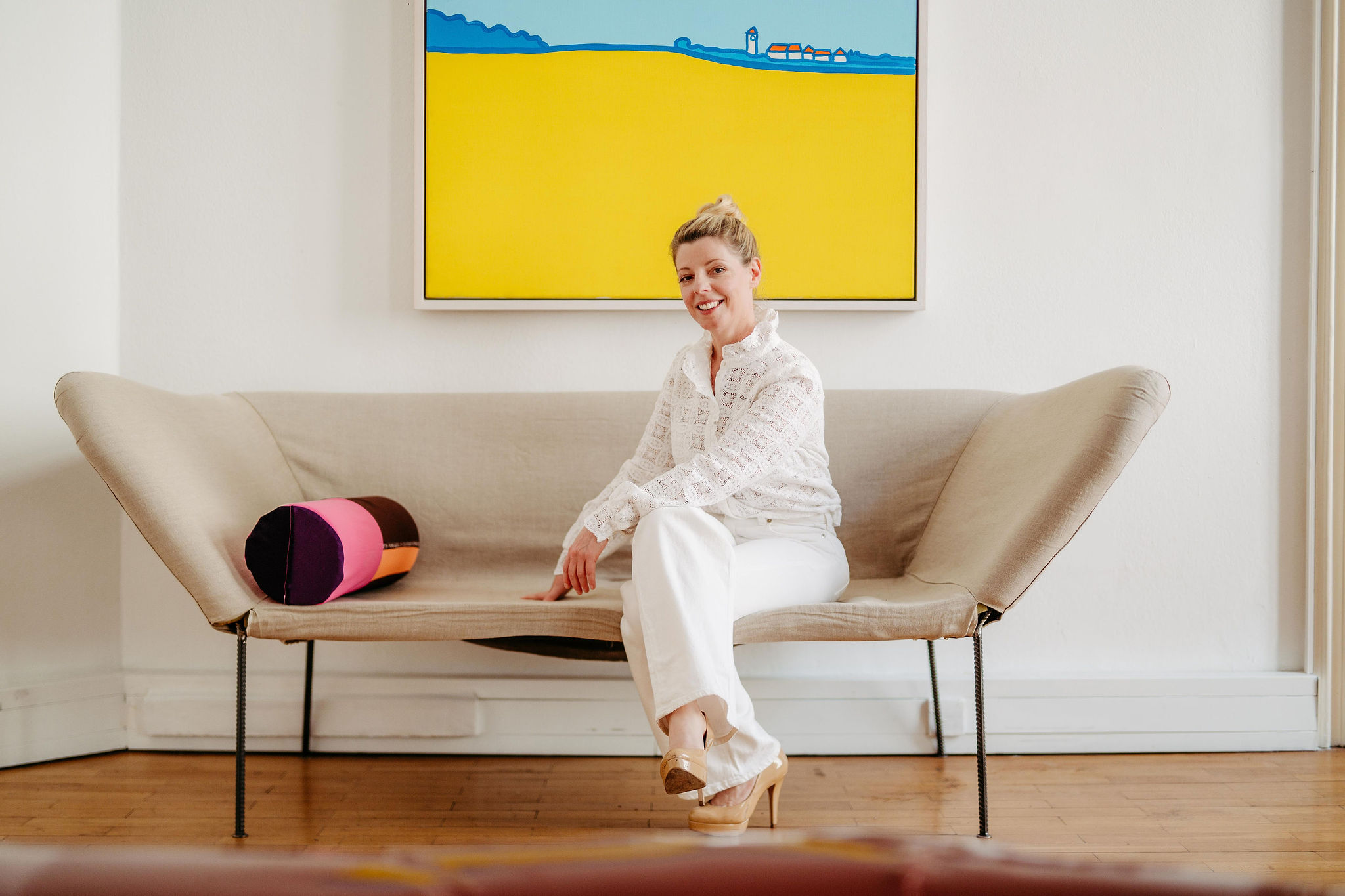 Karin Lischka auf einem Sofa vor einem farbenfrohen Gemälde